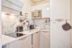 a white kitchen with white cabinets and appliances at Appartement classé 2 étoiles à Cabourg - Proche plage et centre-ville in Cabourg +10 photos