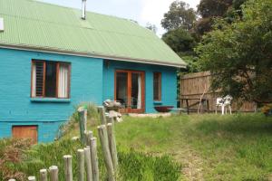 a blue house with a green roof and a fence at Yellowwood Place in Bettyʼs Bay