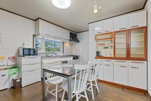 une cuisine avec des armoires blanches et une table et des chaises dans l'établissement Yotei View House, à Kutchan