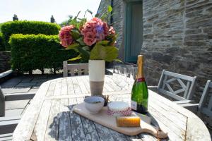 una mesa con un jarrón de flores y una botella de vino en The Dovecote Llechryd, en Llechryd