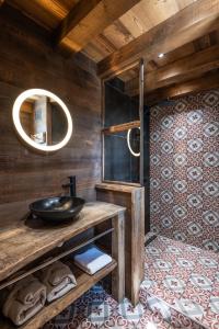ein Badezimmer mit einem Waschbecken und einer Holzwand in der Unterkunft Chalet 1907, pleine vue lac in Gérardmer