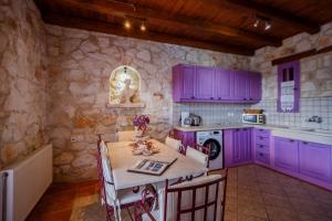 une cuisine avec des armoires violettes et une table dans l'établissement Villa Carolina, à Áyios Dhimítrios