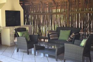 a living room with a couch and chairs and a tv at Impangele Lodge in Muldersdrift