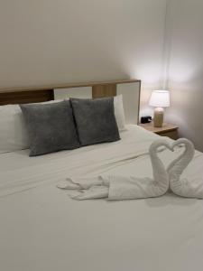 Una cama blanca con dos toallas en forma de corazón. en เพชรไพลินรีสอร์ทสามร้อยยอด, en Sathani Sam Roi Yot
