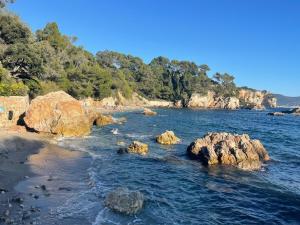 a beach with rocks in the water and trees at Maison Cap Brun Jardin Parking in Toulon
