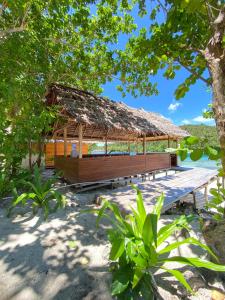 a wooden pavilion with a straw roof on a beach at Marlina Homestay in Fam +62 photos
