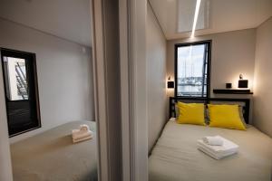 a bedroom with a bed with yellow pillows and a window at The Homeboat Company Ponta Delgada-Açores in Ponta Delgada