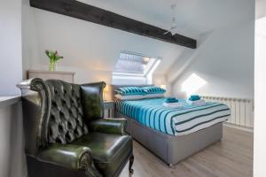 1 dormitorio con 1 cama y silla de cuero en Old Stables Loft, en Kendal