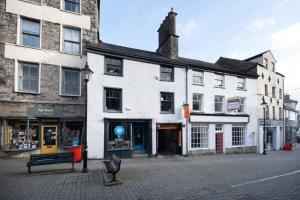 Un gran edificio blanco en una calle con un banco. en Old Stables Loft, en Kendal