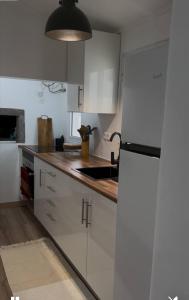 a kitchen with white cabinets and a black refrigerator at Casinha Santa Maria in Vila do Porto +9 photos