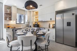a kitchen with a table with chairs and a refrigerator at Upscale 4BR Villa, Bali Pool, Resort Escape in Dubai