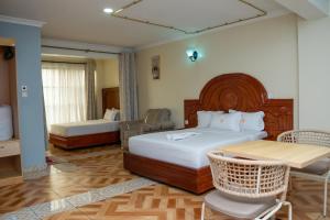 a bedroom with two beds and a table and chairs at The Mark Hotel in Ruiru