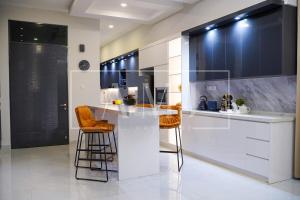 a kitchen with white cabinets and orange bar stools at Cyberjaya Luxury Pool Villa Corner lot 16-20 pax in Puchong