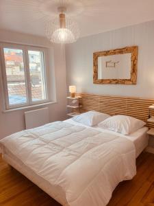 a bedroom with a large white bed and a chandelier at La Parenthèse Marine in Étaples