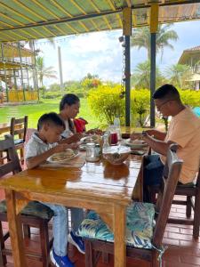 a family sitting at a wooden table eating food at Finca Hotel el Palmar in Montenegro