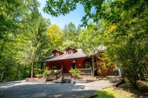 een rood huis in het bos met bomen bij Adventure Lodge in Gatlinburg