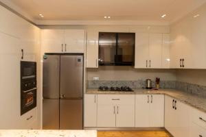 a kitchen with white cabinets and a stainless steel refrigerator at Steeze Apartment in Mama
