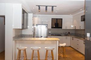 uma cozinha com armários brancos e um balcão com bancos em Steeze Apartment em Mama mais 13 fotografias