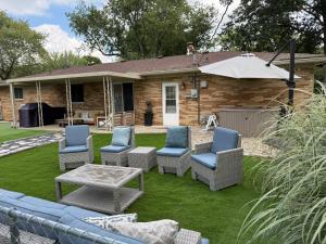 a patio with chairs and a table and an umbrella at Delightful 3 Bd Home with King size bed, hot tub, playground! in Indianapolis