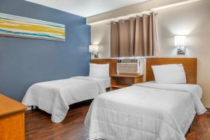 two beds in a room with blue walls at HomeTowne Studios by Red Roof Louisville in Louisville