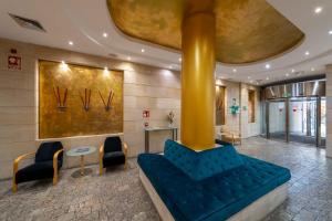a lobby with a blue couch and chairs in a building at Eurostars Rey Alfonso X in Ciudad Real