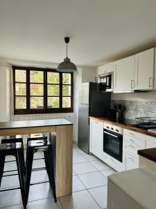 a kitchen with white cabinets and a black refrigerator at Maison de charme " Les Cyclamens" in Saint-Jorioz