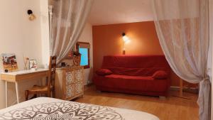a bedroom with a red bed and a red couch at Logis des Lauriers Roses in Marennes