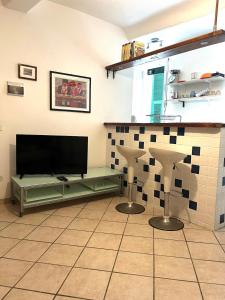 a living room with a flat screen tv and two stools at Lerici, tra i carruggi e il mare in Lerici