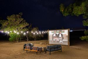 a billboard with two chairs and a sign in the dirt at Desert Haven, Pickleball, Stargazing, Spa & Views in Joshua Tree +73 photos