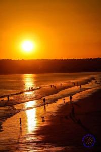 eine Gruppe von Menschen am Strand bei Sonnenuntergang in der Unterkunft Charming Shepherd's Cottage, Pets Welcome,parking in Bridgend
