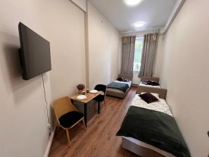 Habitación con 2 camas, TV y mesa. en Hostel KASZUBSKA, en Wroclaw