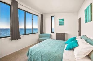 a bedroom with a bed and a chair and windows at Waterfront Haven with Spectacular View in Bainbridge in Rollingbay +35 photos