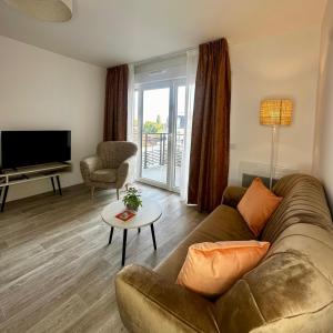 a living room with a couch and a television at Les Belles Lettres in Herblay