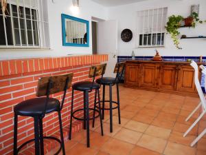 a kitchen with four bar stools against a brick wall at Chalet con Jardin Piscina Privada y parking in Valencina de la Concepción