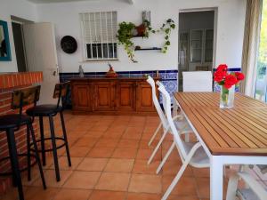 a kitchen with a wooden table and white chairs at Chalet con Jardin Piscina Privada y parking in Valencina de la Concepción +17 photos