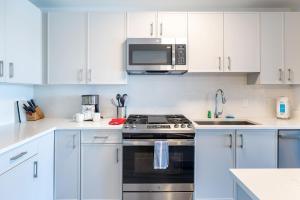 a white kitchen with a stove and a microwave at Luxury Apartment in Stamford - Gym & Pool Access in Stamford