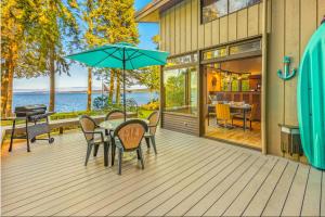 a patio with a table with chairs and an umbrella at Poulsbo Waterfront Lodge with Game Room Library in Port Gamble