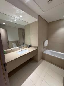 a bathroom with a sink and a tub and a mirror at Central 2br Apt Yas F1 Circuit in Abu Dhabi