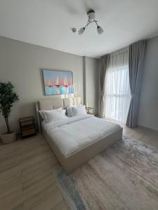 a bedroom with a large white bed in front of a window at Central 2br Apt Yas F1 Circuit in Abu Dhabi +13 photos