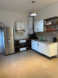 Una cocina con gabinetes blancos y un refrigerador de acero inoxidable. en Colibrí - Smart Hostel, en San Juan