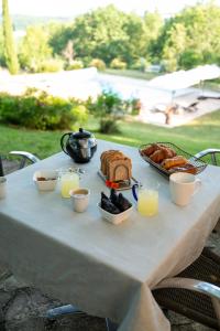 a table with a breakfast of bread and orange juice at La bastide de Meilhouret in Larroque