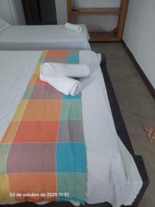 deux serviettes sur un lit avec une couverture colorée dans l'établissement Pousada e Hostel La Civetta - Maresias, à São Sebastião
