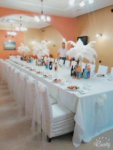 a long table with white chairs and a man in a room at Casa Maria Magdalena in Văleni