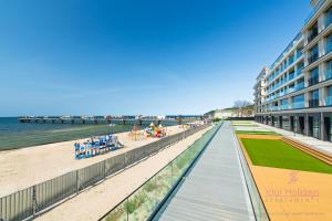 Una pasarela junto a la playa y un edificio. en Your Holidays Infinity A227, en Międzyzdroje