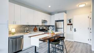 a kitchen with white cabinets and a counter with stools at Modern Townhome - Walk to Yale and Downtown in New Haven