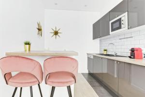 a kitchen with two pink chairs at a counter at Convinient souplex basement 5mn near métro and Montmartre in Paris +7 photos