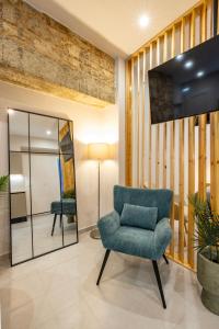 a living room with a blue chair and a mirror at LV Apartments Ioannina in Anatolí +24 photos
