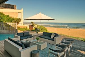 un patio con sillas y una sombrilla y la playa en At Last Glentana Apartment, en Groot Brak Rivier