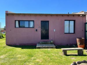a pink house with a bench in front of it at El Cardo in General Belgrano