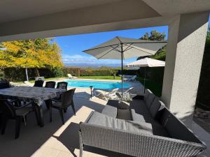 a patio with a table and an umbrella and a pool at Villa ISA 4 bedrooms, 4 bathrooms, sauna, jacuzzi, panoramic view in Vrh